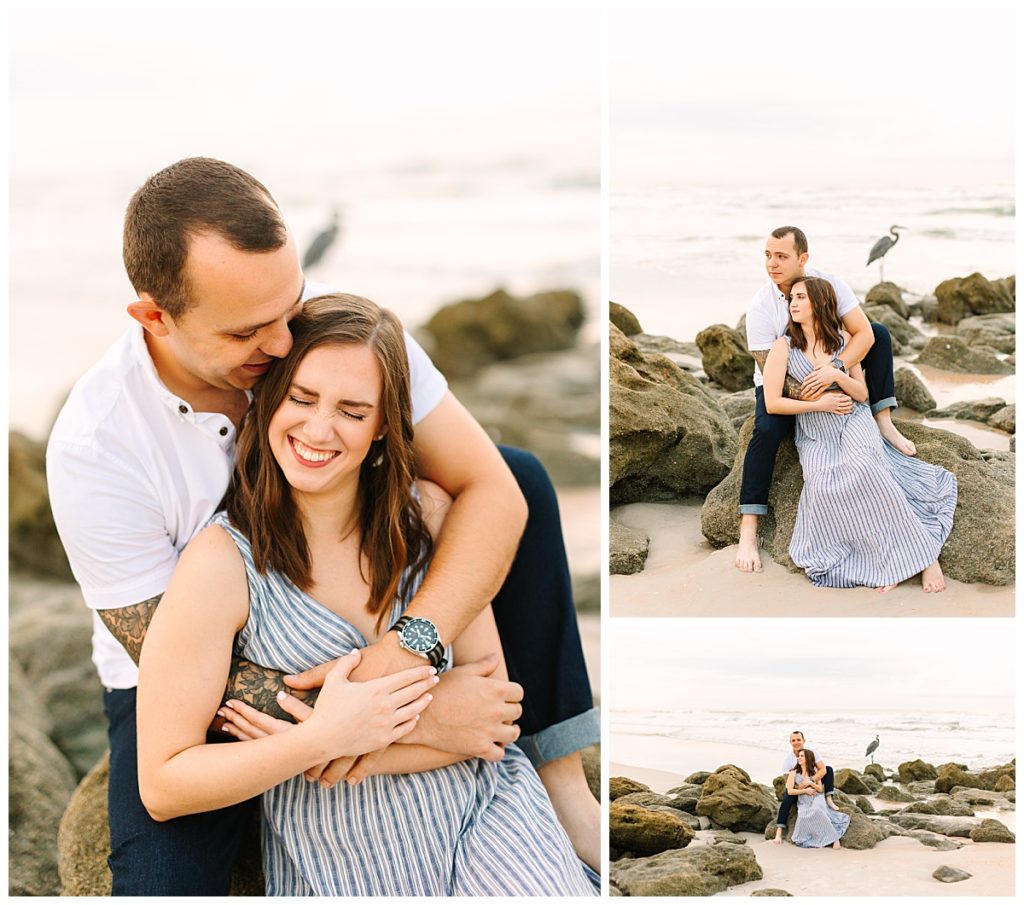 A couple sporting jeans and a blue & white striped dress sit near the Florida shore during their Washington Oaks State Park engagement session. 