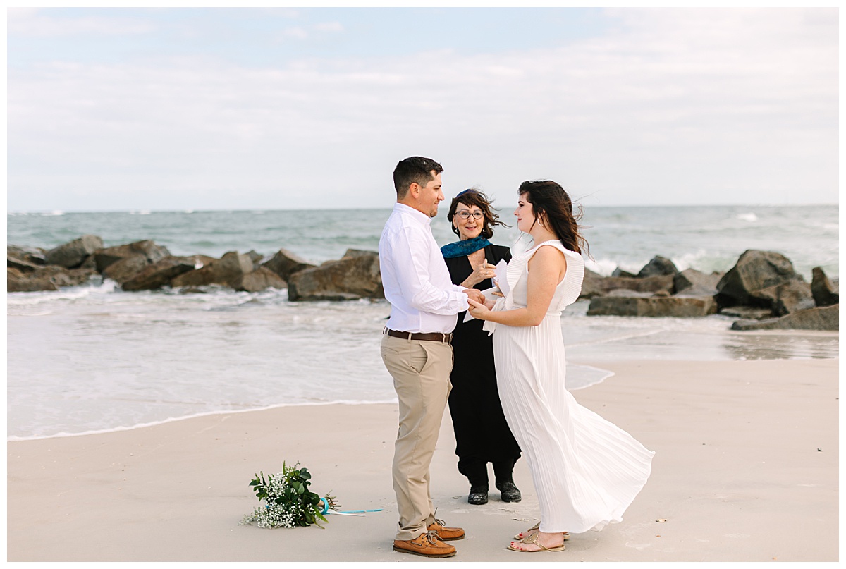A brunette Florida couple wearing a long, white dress and khakis exchange vows on the beach during their elopement ceremony.
