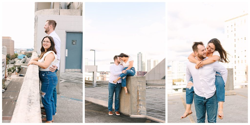 A woman with brown hair wearing a white tank top and jeans poses with her fiance on a downtown Jacksonville, FL rooftop during their engagement session.