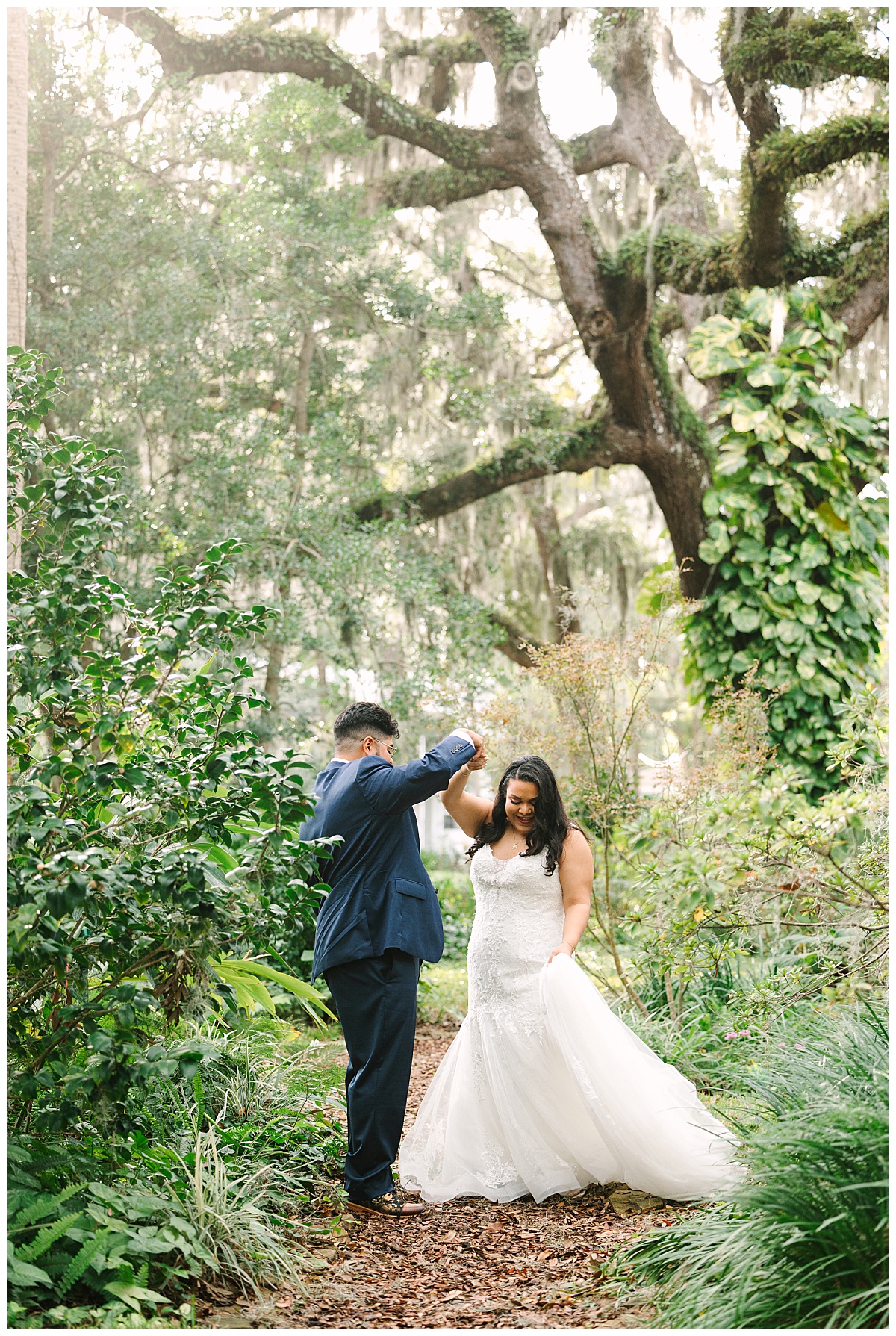 A Florida man twirls his bride in her wedding gown around near Spanish Moss covered trees.