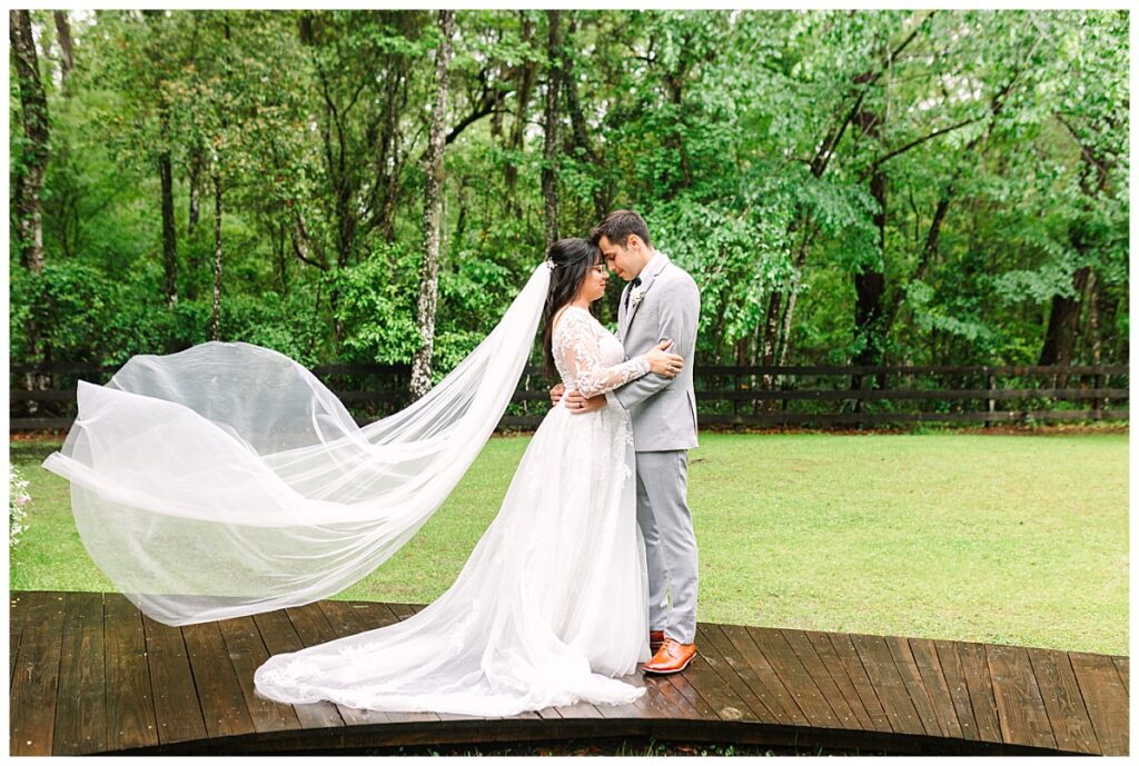 A newly married couple embrace in their wedding gown and suit on a rainy walkway at Tucker's Farmhouse after their wedding.