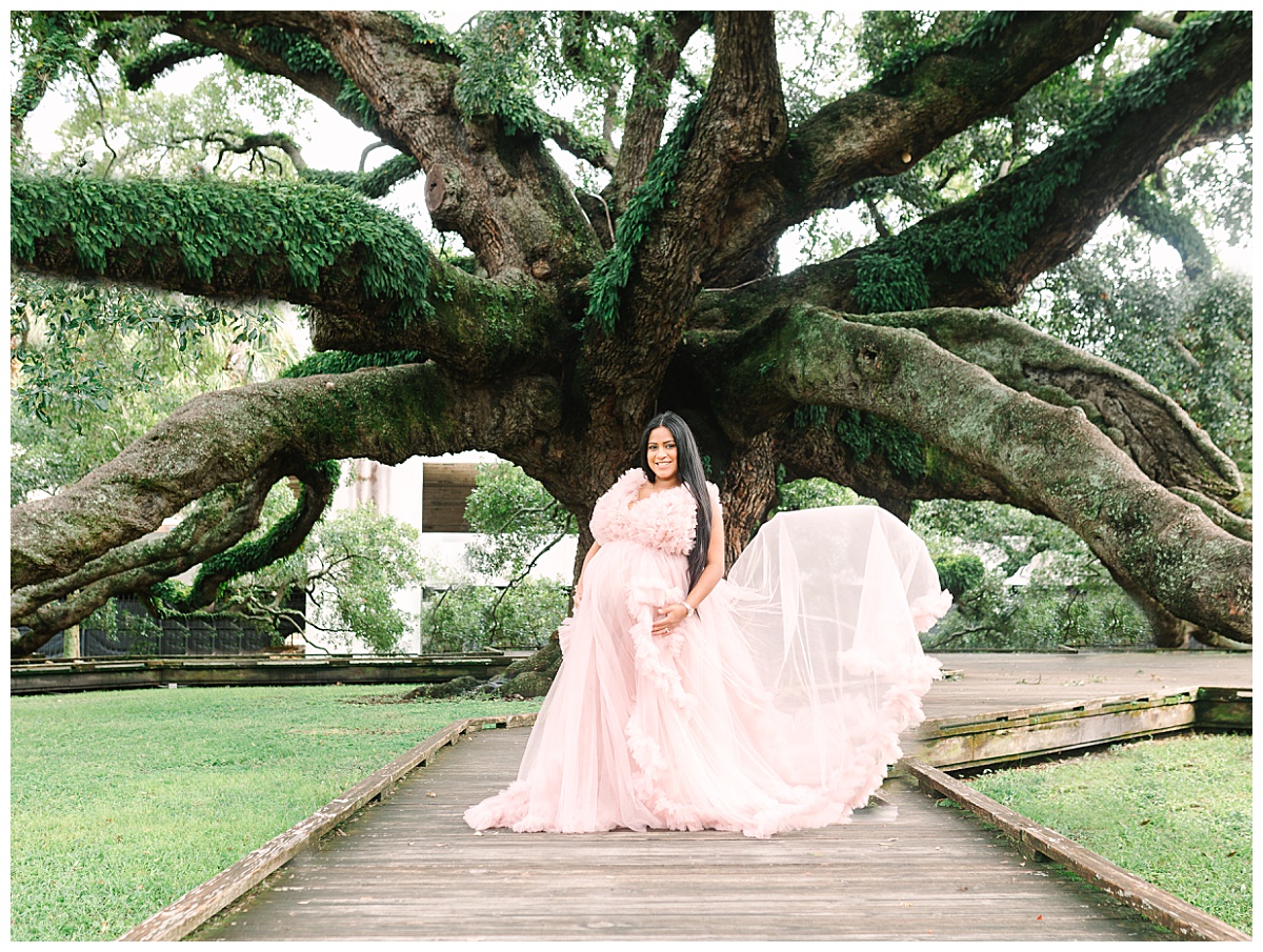 An expectant mother holds her baby bump in front of Treaty Oak in Jacksonville, FL.