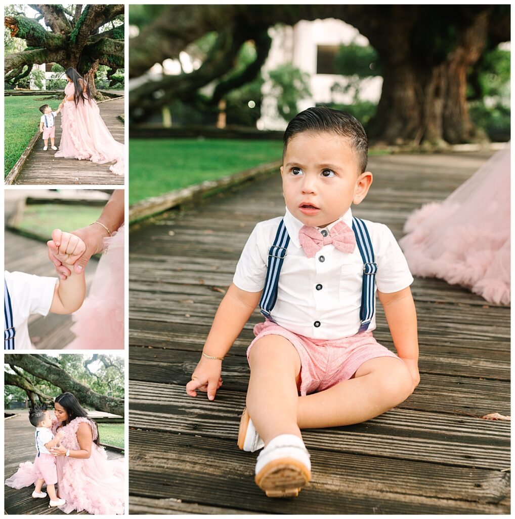 A toddler boy with black hair wearing blue suspenders with a shorts outfit poses with his mother in a pink, flowing maternity gown during her Florida maternity session.